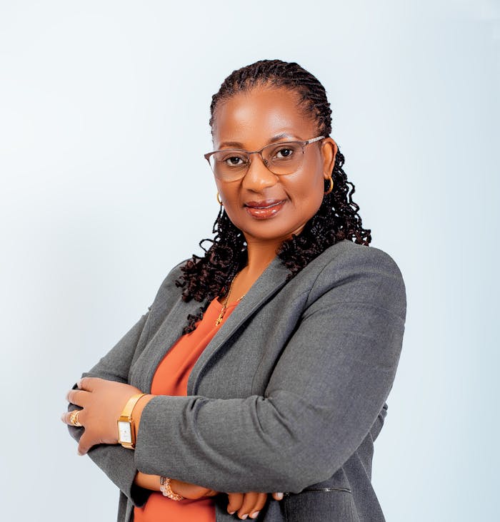 gallery-06 Confident woman in glasses, wearing a business suit, smiles with arms crossed.