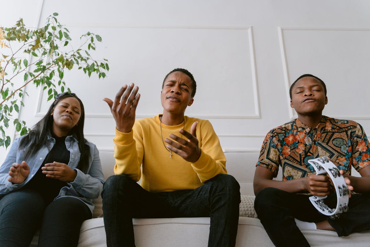gallery-04 Three people singing and playing a tambourine, expressing friendship and joy indoors.